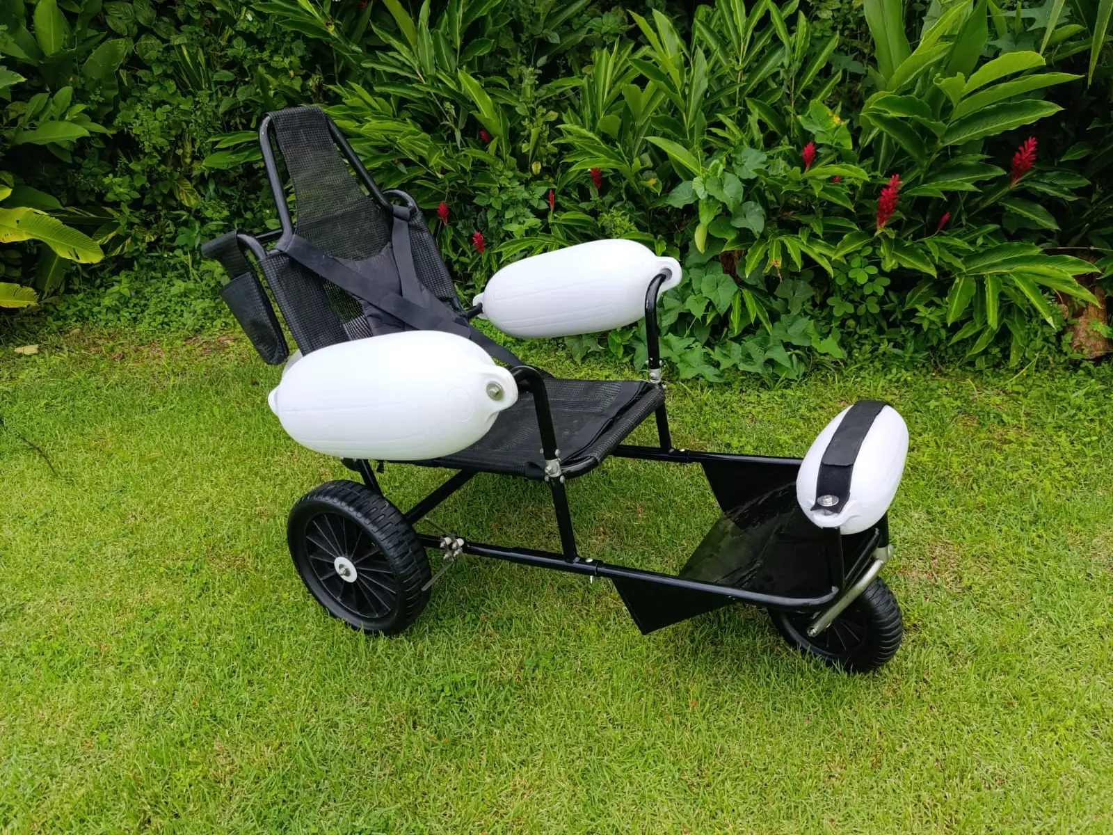 Cadeira anfíbia Mareia Flex à direita de um jardim gramado, com design ergonômico em destaque.